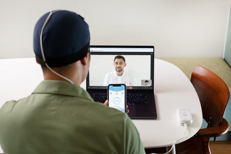 A clinician instructs a patient on use of Sooma tDCS through a video call